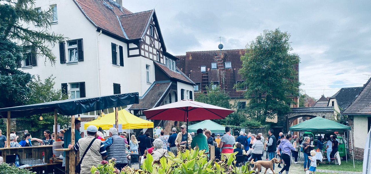 Lebendiges Hoffest im Pfarrhof Igstadt Gut besuchtes Hoffest im Innenhof des Igstadter Gemeindezentrums mit Marktständen, Pavillons und zahlreichen Besuchern vor dem historischen Pfarrhaus mit Fachwerk-Elementen